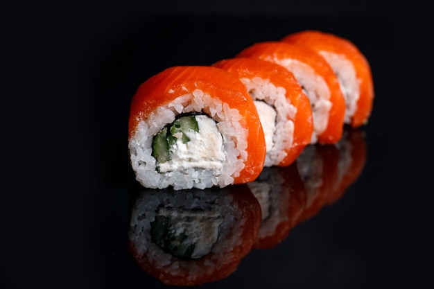 Philadelphia Sushi Roll auf einem schwarzen Hintergrund mit Reflexion.