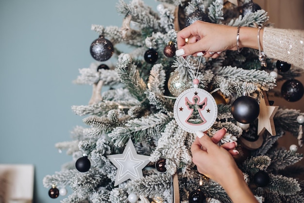 Phoro recortada de manos de dama sosteniendo un hermoso juguete de ciervo cerca del árbol de Navidad. Concepto de víspera de año nuevo