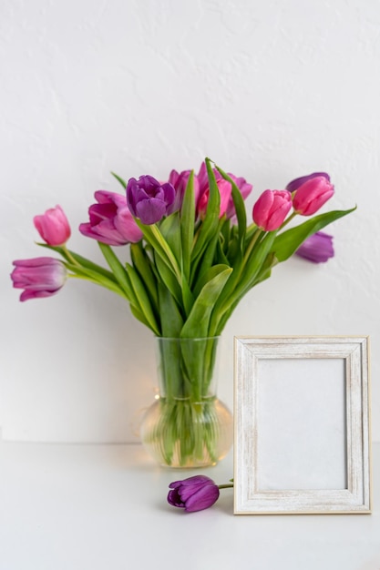Photofame-Attrappe auf Tisch mit Vase mit Tulpen