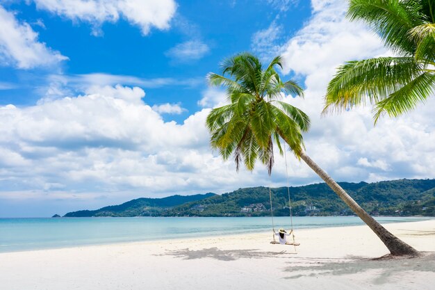 Phuket, Tailandia, un paraíso de playa tropical con columpio en la playa con una chica con camisa blanca