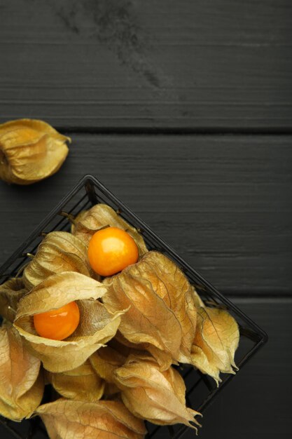 Physalis peruviana Frucht auf schwarzem Holzhintergrund Vertikales Foto