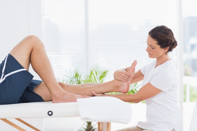 Physiotherapeut, der Beinmassage tut