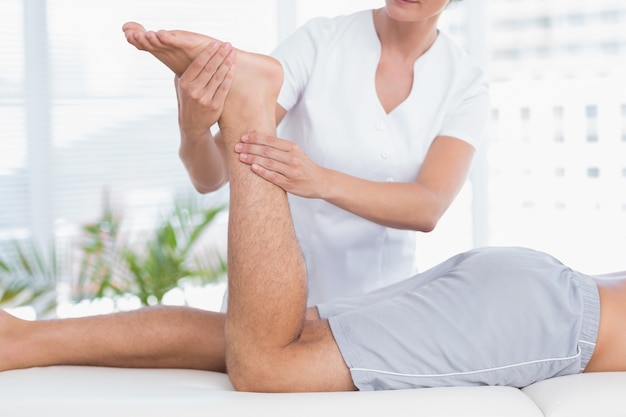 Physiotherapeut, der Beinmassage zu ihrem Patienten tut