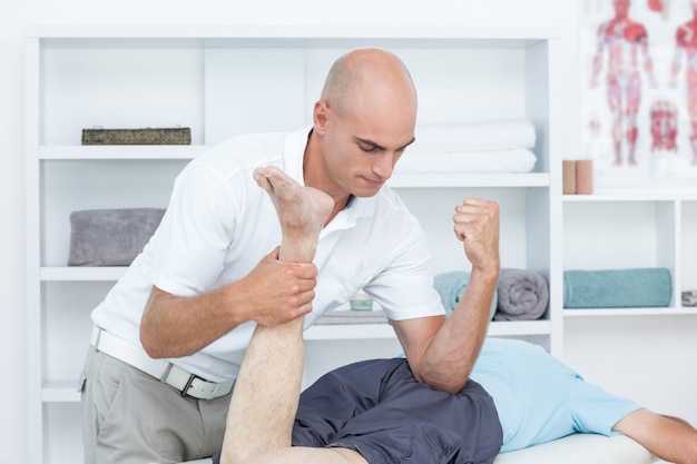 Physiotherapeut, der Beinmassage zu seinem Patienten tut