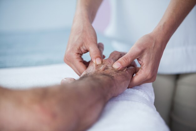 Physiotherapeut, der dem Patienten Handmassage gibt