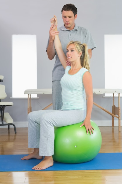 Foto physiotherapeut, der den patienten sitzt auf übungsball korrigiert
