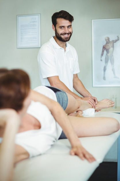 Physiotherapeut, der einer Frau Beinmassage gibt