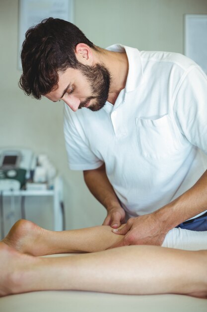 Physiotherapeut, der einer Frau Beinmassage gibt