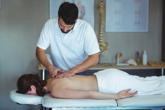 Physiotherapeut, der einer Frau eine Rückenmassage gibt