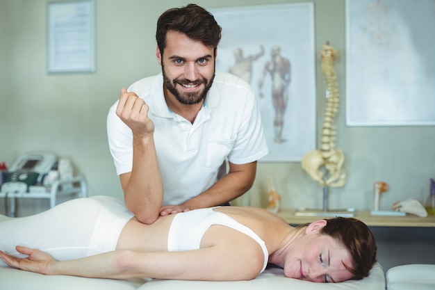 Physiotherapeut, der einer Frau eine Rückenmassage gibt