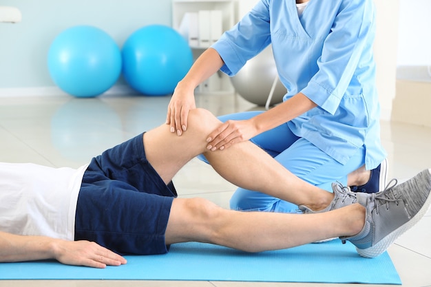 Physiotherapeut, der mit männlichen Patienten im Rehabilitationszentrum arbeitet