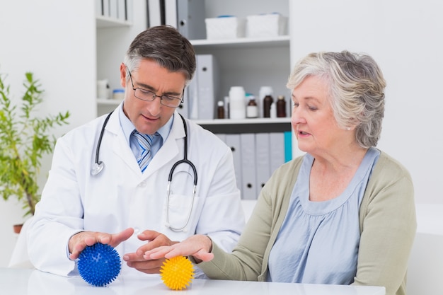 Physiotherapeut, der weiblichen Patienten mit Massageball führt