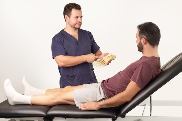 Physiotherapeut erklärt einem Patienten, was seine Fußverletzung ist, und zeigt ihm ein Fußskelett