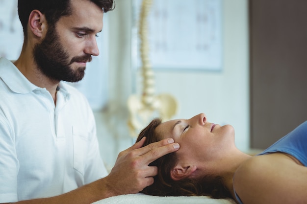 Physiotherapeutin, die einer Frau eine Kopfmassage gibt