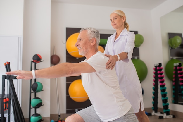 Physiotherapeutin im Laborkittel, die mit einem Patienten arbeitet