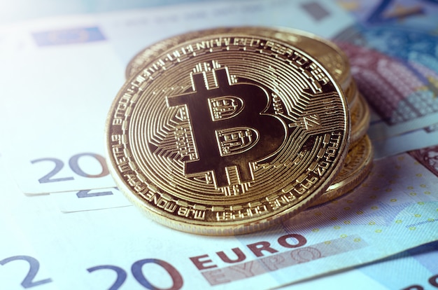 Physische Gold-Bitcoin-Münze gegen Euro-Scheine.