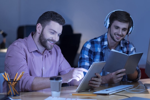 Piada engraçada. Homem feliz, positivo e encantado lendo piadas na Internet e rindo durante uma pausa no trabalho