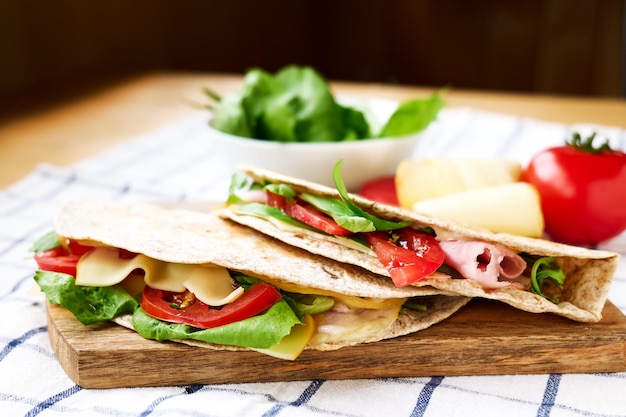 Foto piadina romagnola com mozzarella queijo tomate presunto e salada de foguete em uma tábua de corte