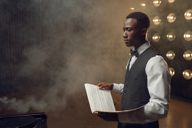 Pianista de ébano com caderno de música no palco