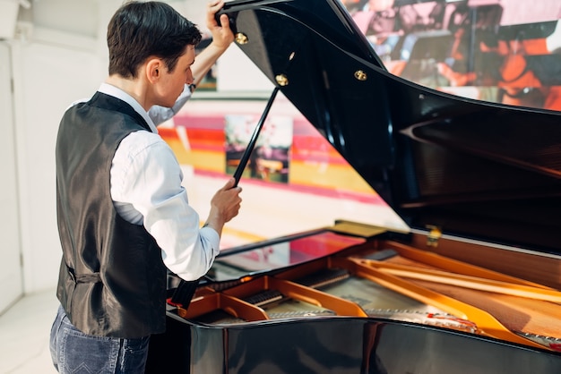 Pianista masculino abre a tampa do piano de cauda preto