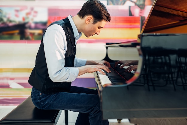 Pianista masculino practicando composición en piano de cola