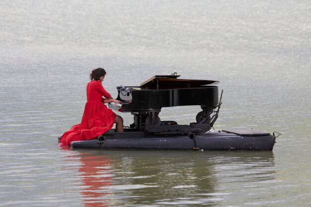 Foto pianista tocando piano no lago