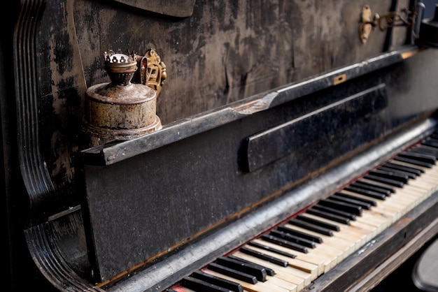 Piano arruinado con candelabros oxidados y teclado desgastado con teclas rotas de cerca