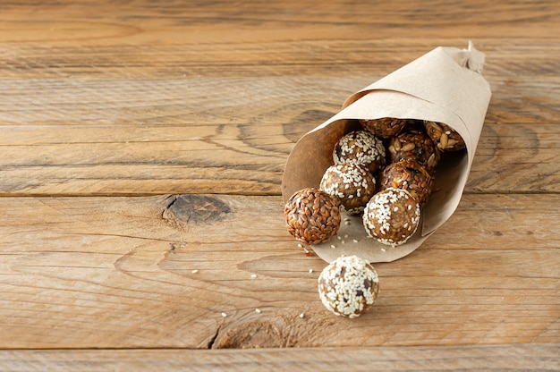 Picadas de energia com nozes, sementes, frutas secas e mel - picadas de granola de lanche orgânico cru vegetariano ou vegetariano em fundo de madeira.