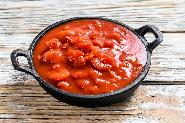 Picado tomates rojos enlatados en una sartén. Fondo blanco. Vista superior