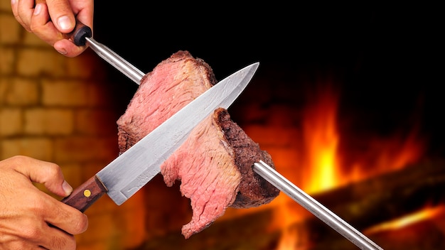 Foto picanha churrasco brasileiro assado na brasa faca cortando um pedaço de carne no espeto