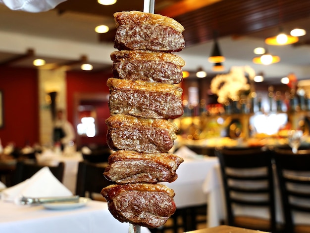 Picanha tradicional bife brasileiro no churrasco Fatias de picanha grelhada no espeto Fundo do restaurante