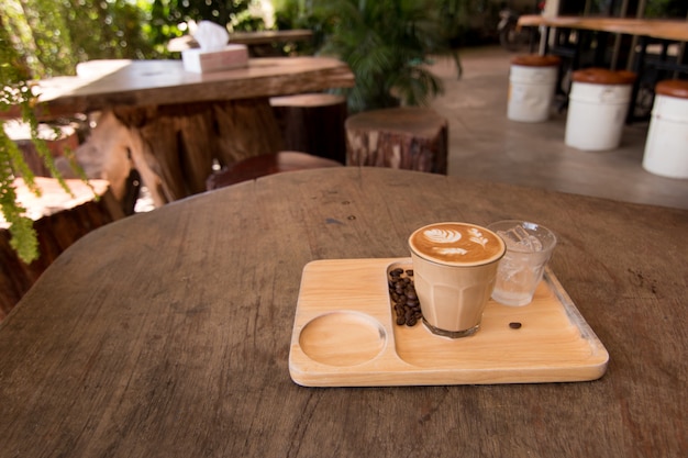 Piccolo Latte art em copo pequeno na mesa de madeira