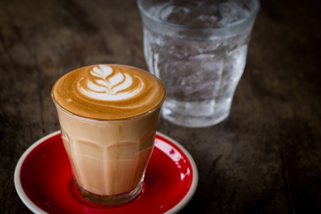 Piccolo Latte arte em vidro pequeno com placa de cerâmica vermelha cobrindo arte de flor bonita do leite