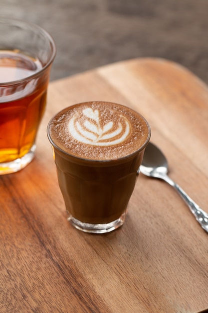 Piccolo Latte arte en vaso pequeño en escritorio de madera