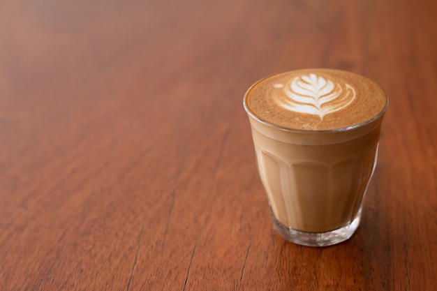 Piccolo Latte-Kunst im kleinen Glas auf hölzernem Schreibtisch