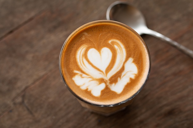 Piccolo Latte-Kunst im kleinen Glas auf hölzernem Schreibtisch