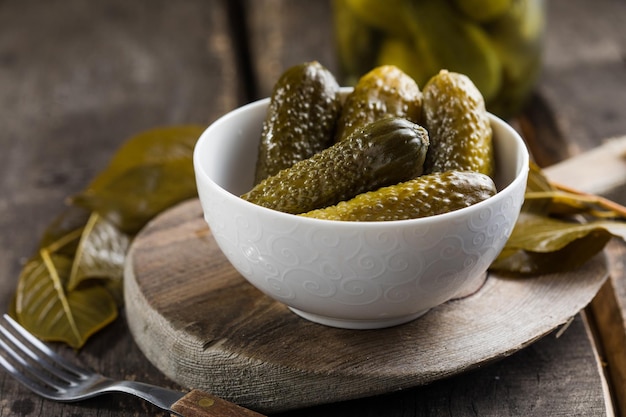 Pickles - in Büchsen fermentierte eingelegte Gurken auf Holzhintergrund. Hausgemachtes sauer mariniertes Gemüse