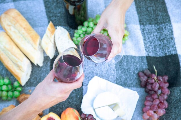 Picknick in der Natur, ein Mädchen und ein Mann halten Gläser mit Wein in den Händen. Selektiver Fokus