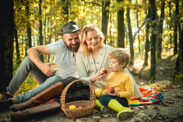 Picknick in der Natur. Familie im Landhausstil. Bedeutung von glückliche Familie. Vereint mit der Natur. Konzept für den Familientag. Glückliche Familie mit dem kleinen Jungen, der sich beim Wandern im Wald entspannt. Mutter-Vater- und kleiner Sohn-Picknick