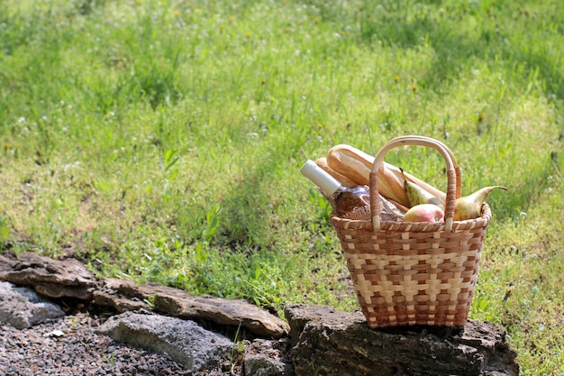 Picknickkorb mit Wein, Obst und anderen Produkten im grünen Gras.