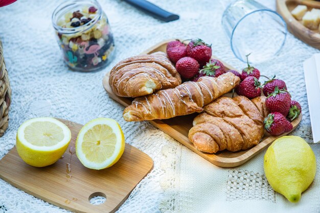 Picnic al aire libre en un exuberante parque verde con un sabroso croissant, rosquillas de frutas y vino sobre el césped