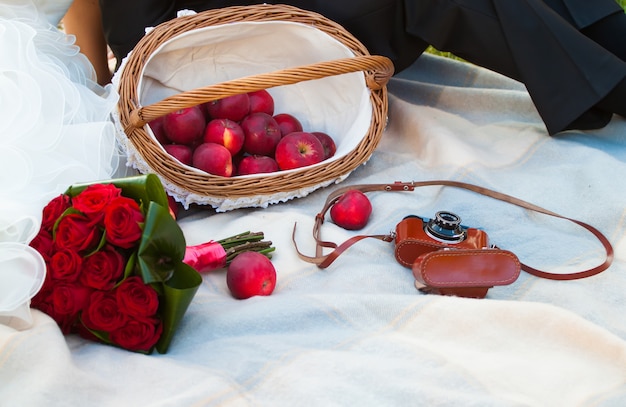 Picnic de boda con manzana, ramo de rosas y cámara antigua