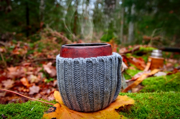 Picnic en el bosque de otoño Taza de arcilla de té caliente sobre musgo verde contra el fondo del bosque de otoño