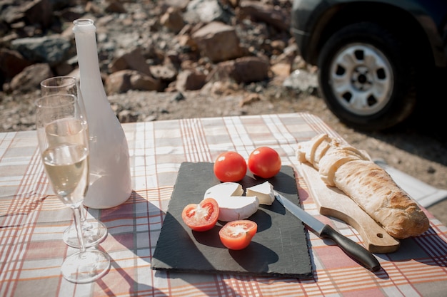 Picnic cerca del agua. familia feliz en un viaje por carretera en su coche. baguette suelta, tomates champán con queso blanco.