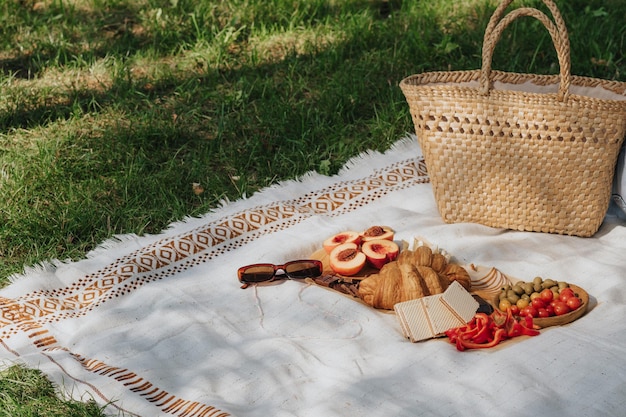 Picnic en el césped con aperitivos ligeros en el contexto de una cesta de paja Desayuno francés