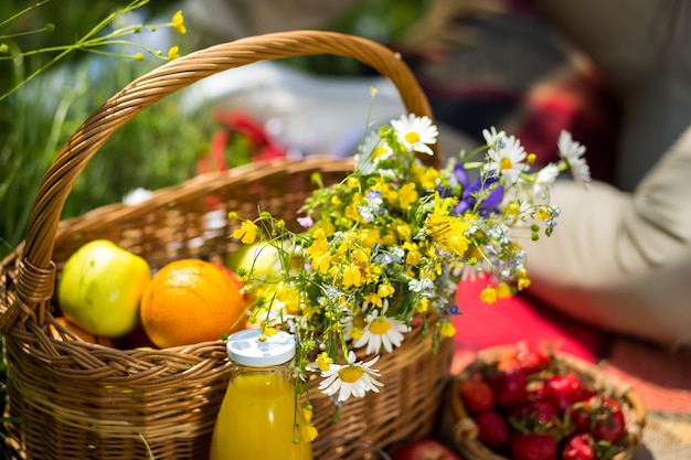 Picnic en el césped con jugo de frutas y ramo de flores silvestres como concepto de comida saludable