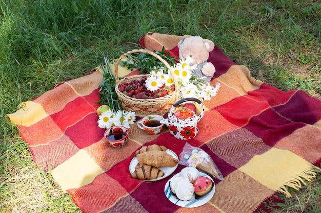 Un picnic con una cesta de comida y flores sobre una manta.