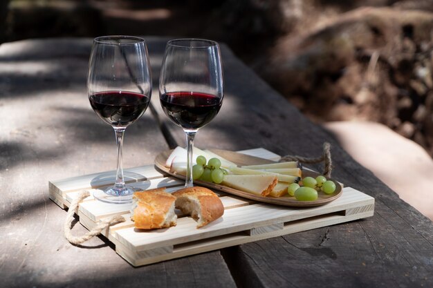 Picnic con copas de vino tinto, pan y queso