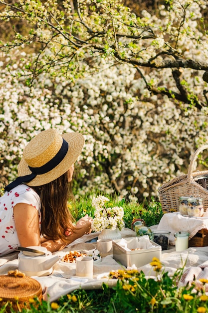 Picnic de pequeno-almoço com waffles e chá no jardim de flores de primavera em uma toalha de mesa branca