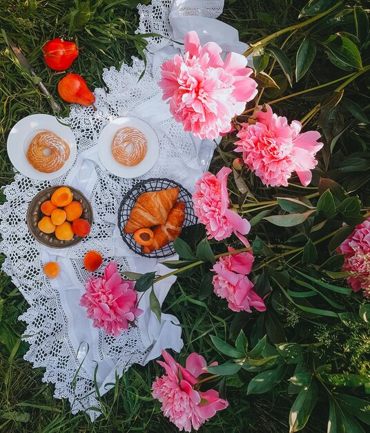 Picnic en estilo antiguo con peonías rosas, frutas y pan, día soleado, enfoque selectivo